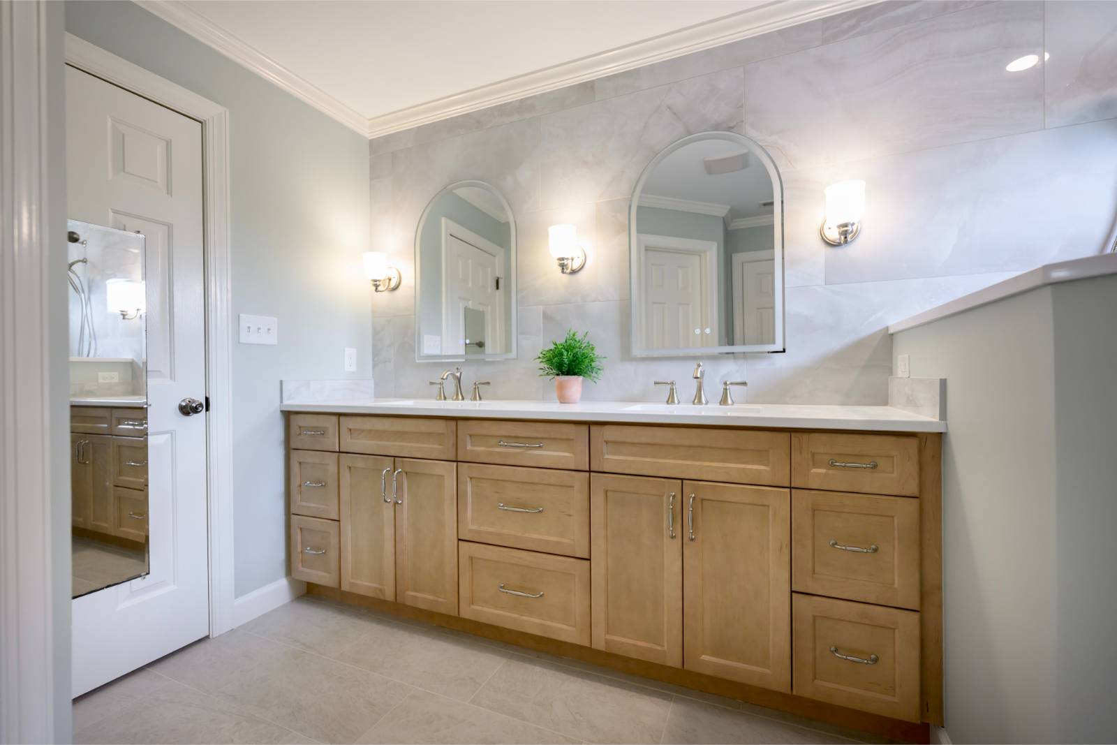 Master bathroom with natural maple double vanity and marble-look tile wall in Raleigh, NC