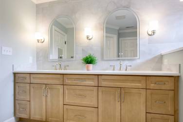 Master bathroom with natural maple double vanity and marble-look tile wall in Raleigh, NC