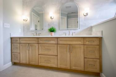 Master bathroom with natural maple double vanity and marble-look tile wall in Raleigh, NC