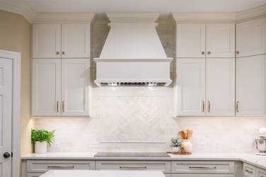 White kitchen with gray island and herringbone tile backsplash in Cary, NC