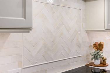 White kitchen with gray island and herringbone tile backsplash in Cary, NC