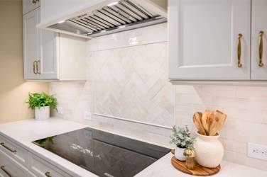 White kitchen with gray island and herringbone tile backsplash in Cary, NC