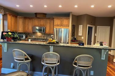 White oak kitchen with sage green island and white quartzite waterfall counters in Raleigh, NC
