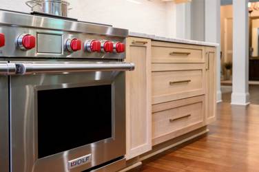 White oak kitchen with sage green island and white quartzite waterfall counters in Raleigh, NC